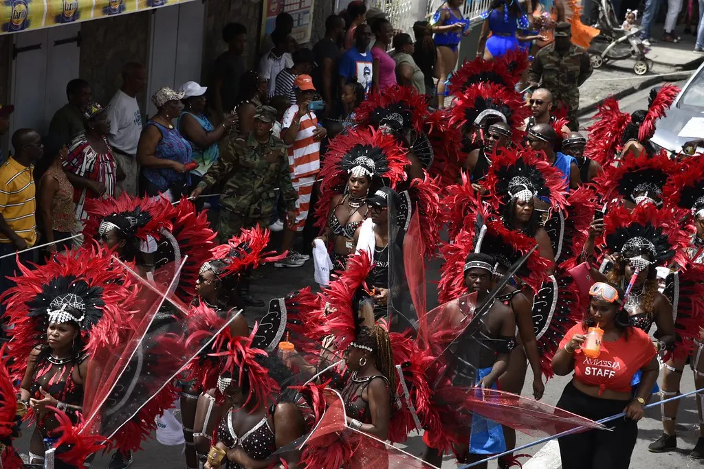 Masqueraders in red feather costumes dancing down the road